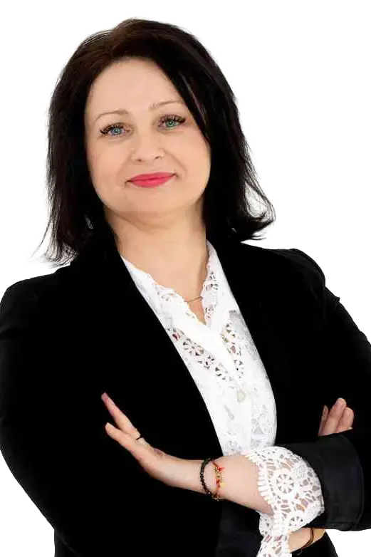 Portret uśmiechniętej kobiety w czarnej marynarce i białej bluzce, z krótkimi ciemnymi włosami, stojącej z założonymi rękami